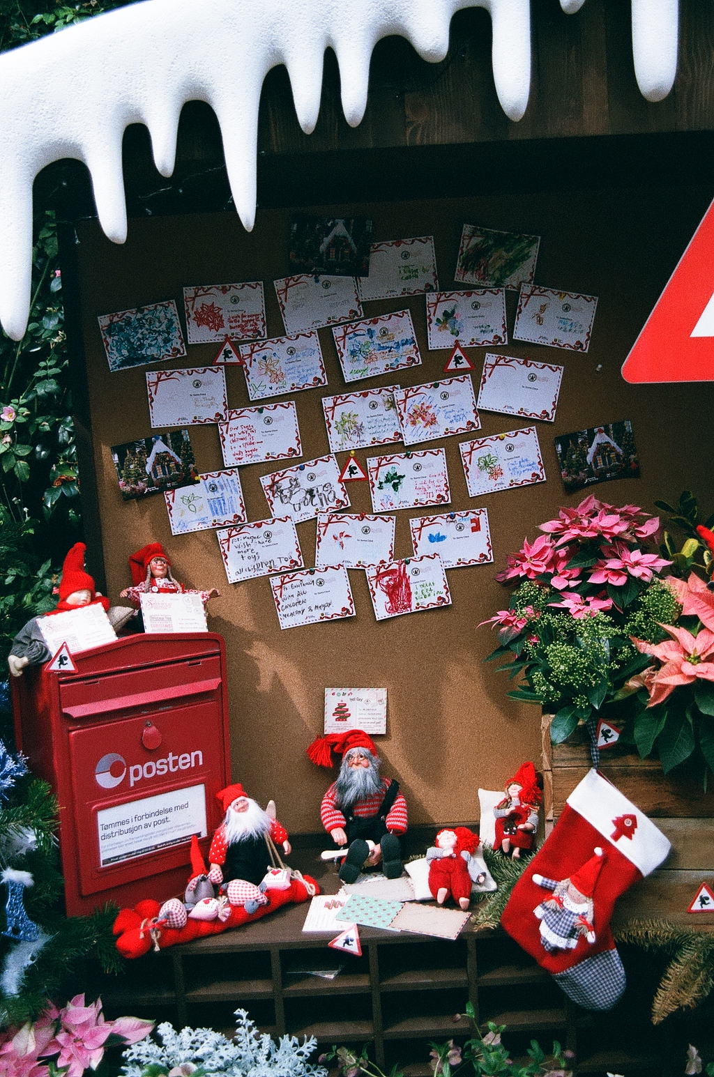 Photo of a Christmas display, with handwritten postcards from children tacked on a cork board and small gnomes for decoration